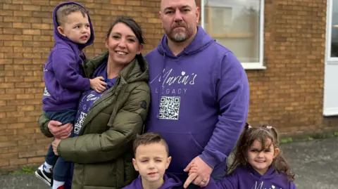 Santino with his wife Michelle and their three younger children Santangelo, Marianna and Santissimo. All are wearing purple tops with the fundraising logo Maria's Legacy.