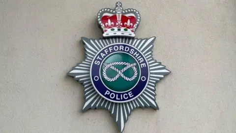 A sign at the headquarters of Staffordshire Police showing the police force's emblem against a white background.