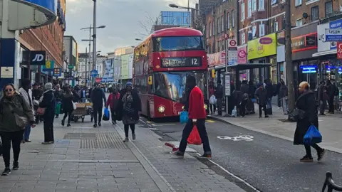 Rye Lane in Peckham - a general view with shoppers and a red London bus.