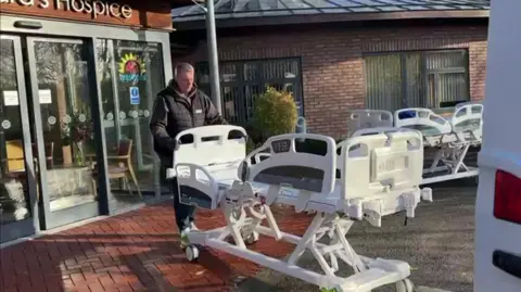 St Leonard's Hospice A cuddle bed being delivered to St Leonard's Hospice in York being pulled by a man in a black jacket with the entrance of the hospice behind him.