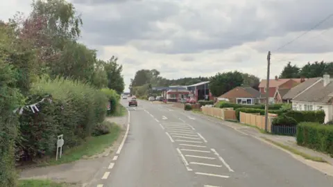 The A52 at Croft Bank. There are trees on the left and bungalows on the right. 