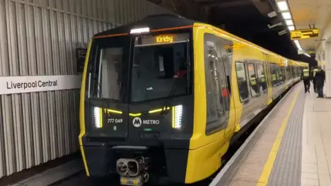 A yellow and black Merseyrail train at the platform in Liverpool Central Station