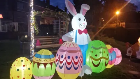 Sandra Lee Myles An inflatable Easter bunny decoration in a garden at night with six colourful inflatable Easter eggs.