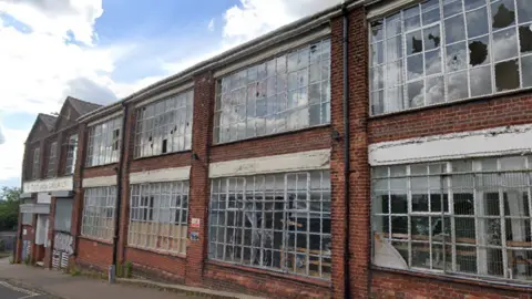 Google Google Street View picture of a disused two-storey brick factory building. Some of its windows are smashed.