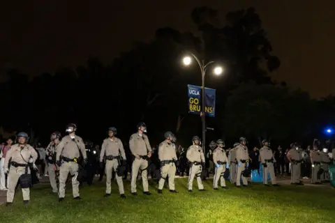 Police officers stand in a row in the dark at UCLA