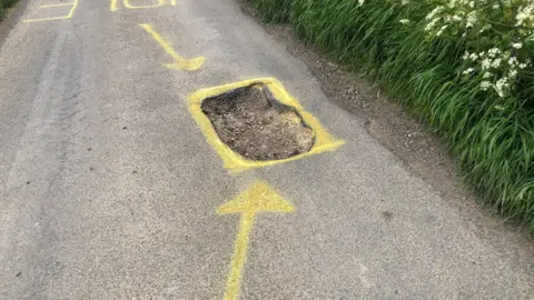 John Devine/BBC Pothole with yellow paint