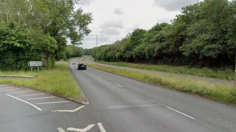 Image of the Warwick Highway which has two lanes on each side of the road. There is grass in between the different directions and trees lining the outside of the road. 