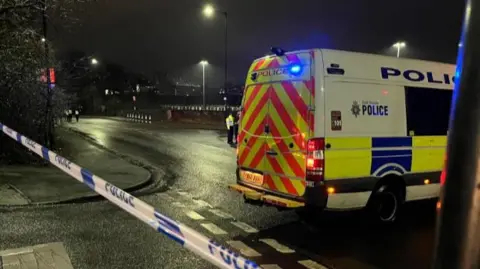 BBC/Oli Constable A police van parked across a taped-off road