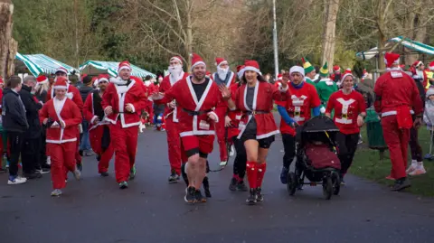 A line up of 10 Santas heading towards the finish line in Victoria Park. Seven me and three women