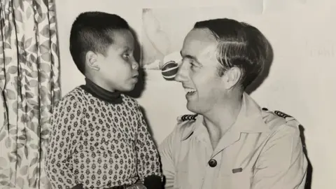 Pritchard family Black and white photo of a boy facing a smiling man in uniform.