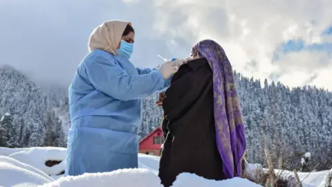 Getty Images A health worker administers a dose of Covishield Coronavirus vaccine to a woman during a door to door vaccination drive in snow at a remote village in Budgam district, about 60kms from Srinagar, in Indian-administered Kashmir 