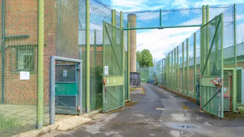A building surrounded by high, green metal fencing.