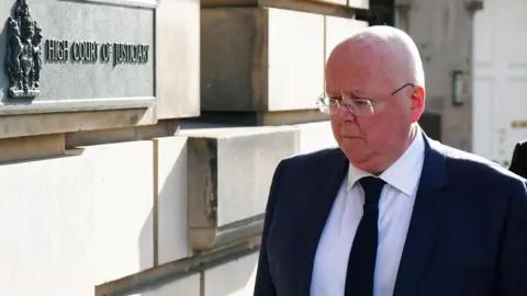PA Media Peter Murrell arrives at court ahead of his guilty plea last Monday. He is wearing a dark suit and tie and a white shirt.