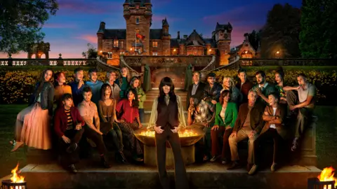 Cody Burridge/Matt Burlem/BBC/Studio Lambert People: (l-r back row) Rachel, Jessie, Stephen, Faraaz, Maz, Ellie, Harriet, Hugo, Jack, Fiona, Sam, Adam, Roxy, Reece (l-r front row) James, Matthew, Jade, Netty, Ross, Judy, Ben, Amanda & Claudia Winkleman - all sitting around a fire pit with a castle behind them. The only person standing is Claudia, in the middle of the image.