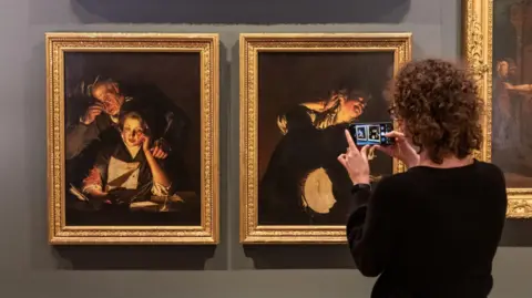 A woman takes a picture of two of Joseph Wright of Derby's pieces at a previous exhibition