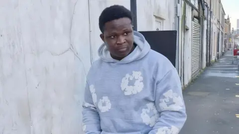 Miracle Oladoyinbo wearing a grey hoodie with white patterns on the front.