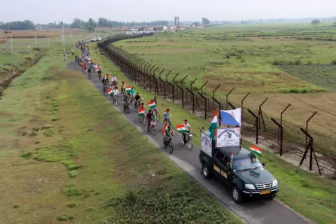 AFP Indian Border Security Force (BSF) personnel, along with the youths, are taking part in a cycle awareness rally at the India-Bangladesh border in Pariyal village near Raiganj, in North Dinajpur district of West Bengal, on May 14, 2024