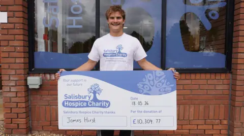 Salisbury Hospice A man holding a large cheque, made out to Salisbury Hospice charity for £10,304. He is smiling widely at the camera.