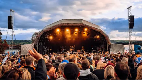 Ania Shrimpton A crowd of people watching a band perform on the main stage