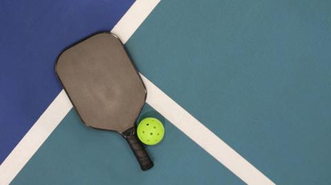 Pickleball bat and ball on court lines