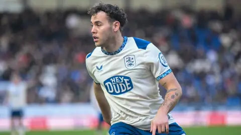Dion Charles in white Huddersfield Town shirt looks to his left during a match