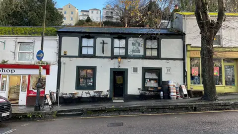 Outside the Moth and Moon pub in Falmouth. Several tables with chairs around them and steel kegs are outside the venue.
