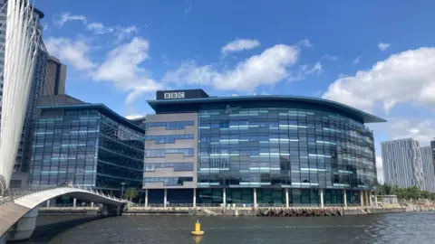 View of MediaCity in Salford. It shows BBC building Quay House with the Manchester Ship Canal in front of it.