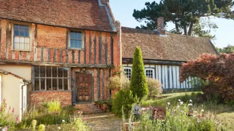 Garden Museum A Tudor home and a garden in front of it. The home is made of red brick and wooden beams. 