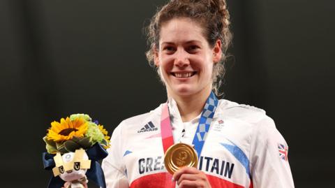Kate French shows off her Olympic gold medal on the podium at Tokyo 2020