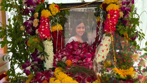 Shahid Shaikh/BBC Marathi A framed photo of a smiling young woman is surrounded by garlands and flowers