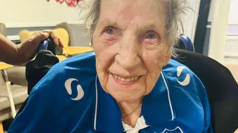 Cosham Court Nursing Home Joan Geary is pictured indoors wearing a blue Pompey football shirt.