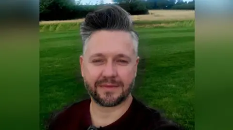 Daniel Tischer A man with a grey beard and grey hair in a field.