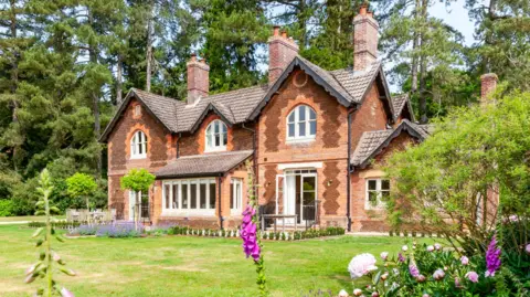 External view of The Gardens House. It is a large building with ornate brick work and lots of chimeys. 