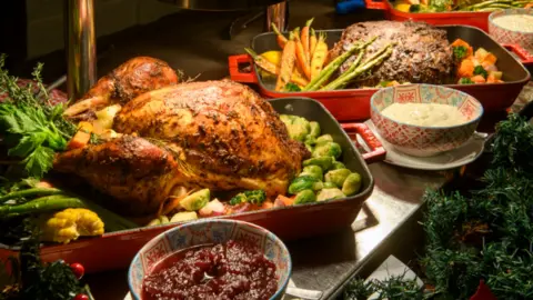 Full cooked turkey on a bed of sprouts with parsnips in the background.