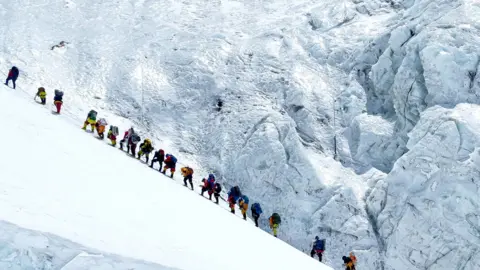 Climbers walk in a long queue as they head to summit Mount Everest in the Solukhumbu distric