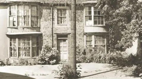 The Worthing Society A sepia-filtered image depicting the front of Stanford's Cottage. A large chestnut tree stands in front of a brick building featuring bow windows across two storeys.