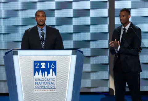 Mike Segar / Reuters Collins speaks into a microphone while standing at a lecturn with a sign reading '2016 Democratic National Convention Philadelphia', while his brother Jarron applauds while standing onstage next to him.