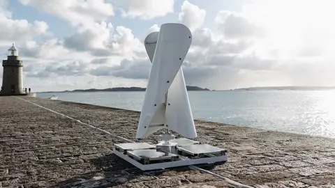 Little Green Energy Company A white wind turbine on a granite pier with a lighthouse and some islands in the background. The wind turbine is made of two curved, vertical sails on a flat base with solar panels on it. It is 1.8m (5.9ft) tall.