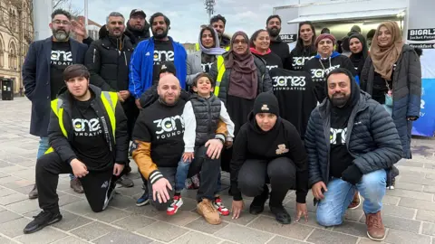 Aisha Iqbal/BBC A group of around 20 people, most wearing T-shirts promoting the 313 Foundation.