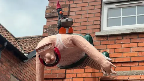 A scarecrow of Wallace and Feathers McGraw from Wallace and Gromit dangles from a property