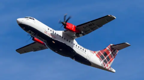 A propeller engine Loganair aircraft in flight. The plane has a white fuselage and tartan decal on its tail. The aircraft is pictured against a cloudless blue sky.