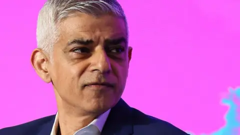 Sadiq Khan against a bright pink background