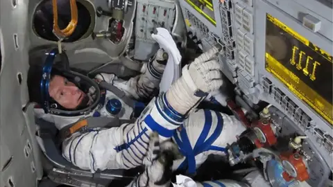 ESA Tim Peake wearing an astronaut suit pushing buttons in board the International Space Station