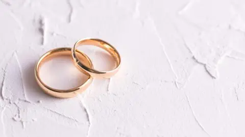 Two gold wedding rings on a white background.