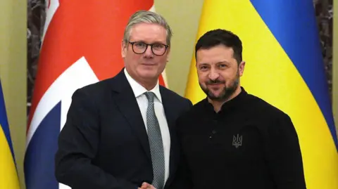 Starmer and Zelensky shake hands in front of a backdrop of UK and Ukraine national flags at the start of press conference at Mariinskyi Palace in Kyiv