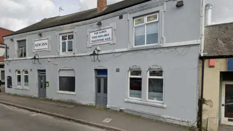 Google A light grey-fronted pub building with a sign saying New Inn on the front.