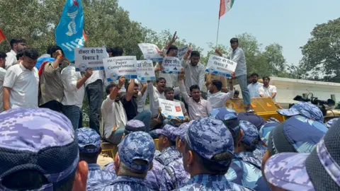 NSUI/X Protesters standing on barricades holding placards which read the medical entrance test is compromised as police personnel push them back 