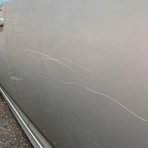Scrapes on the side of silver-coloured car