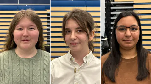Ben Schofield/BBC A composite image of three girls all looking down the camera. On the left is Ella, who is smiling and wearing a light green cable-knit top. In the middle is Sara, who is wearing a white, open-necked shirt. On the right is Suriya, who is wearing a round-necked, light brown top and glasses. They are all standing inside.