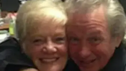 Family photo Sheila Jackson, who has blonde hair and is 83 years old, is photographed hugging her partner Peter Greener, 77, who has swept-back grey hair. 